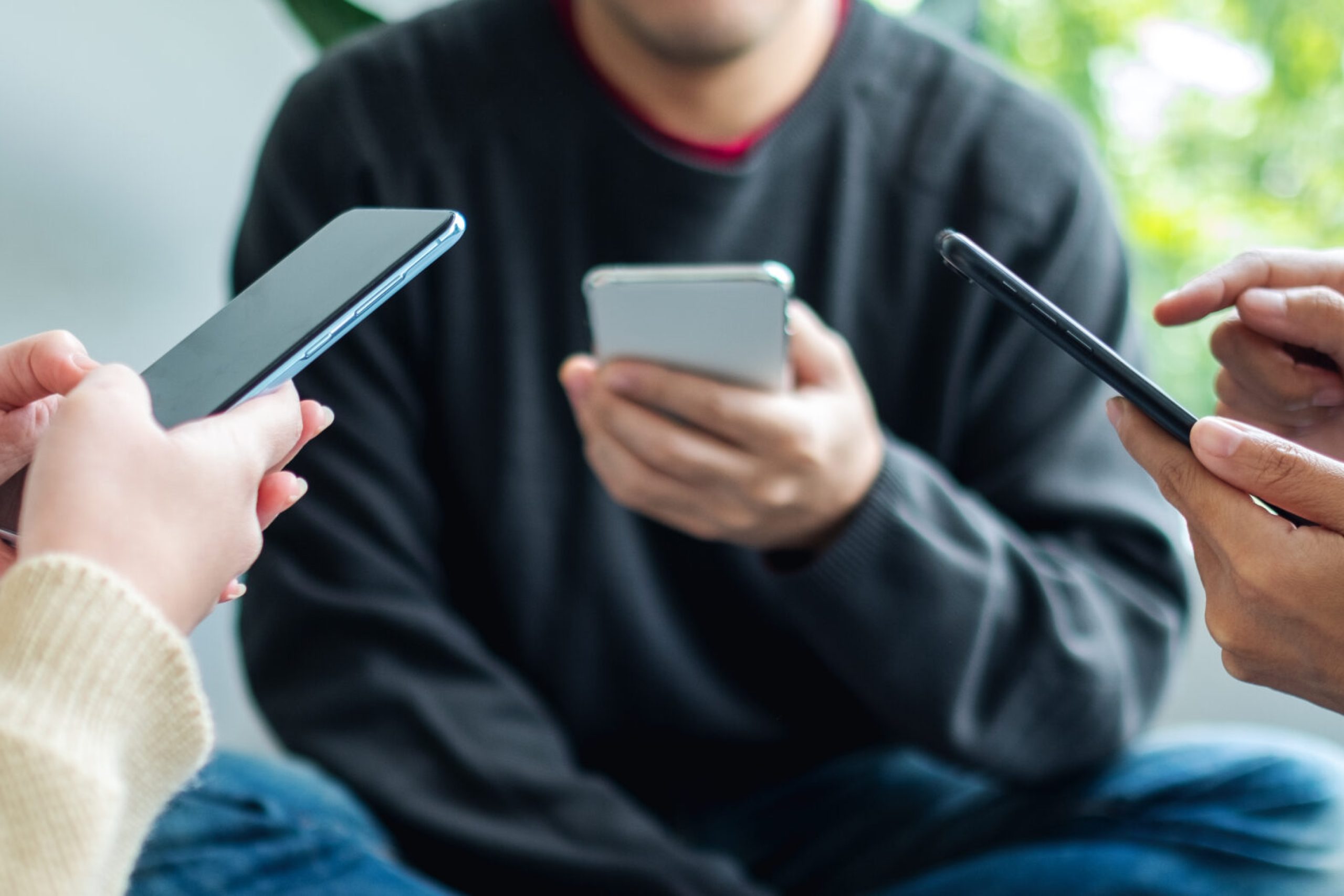 Group of young people using and looking at mobile phone together